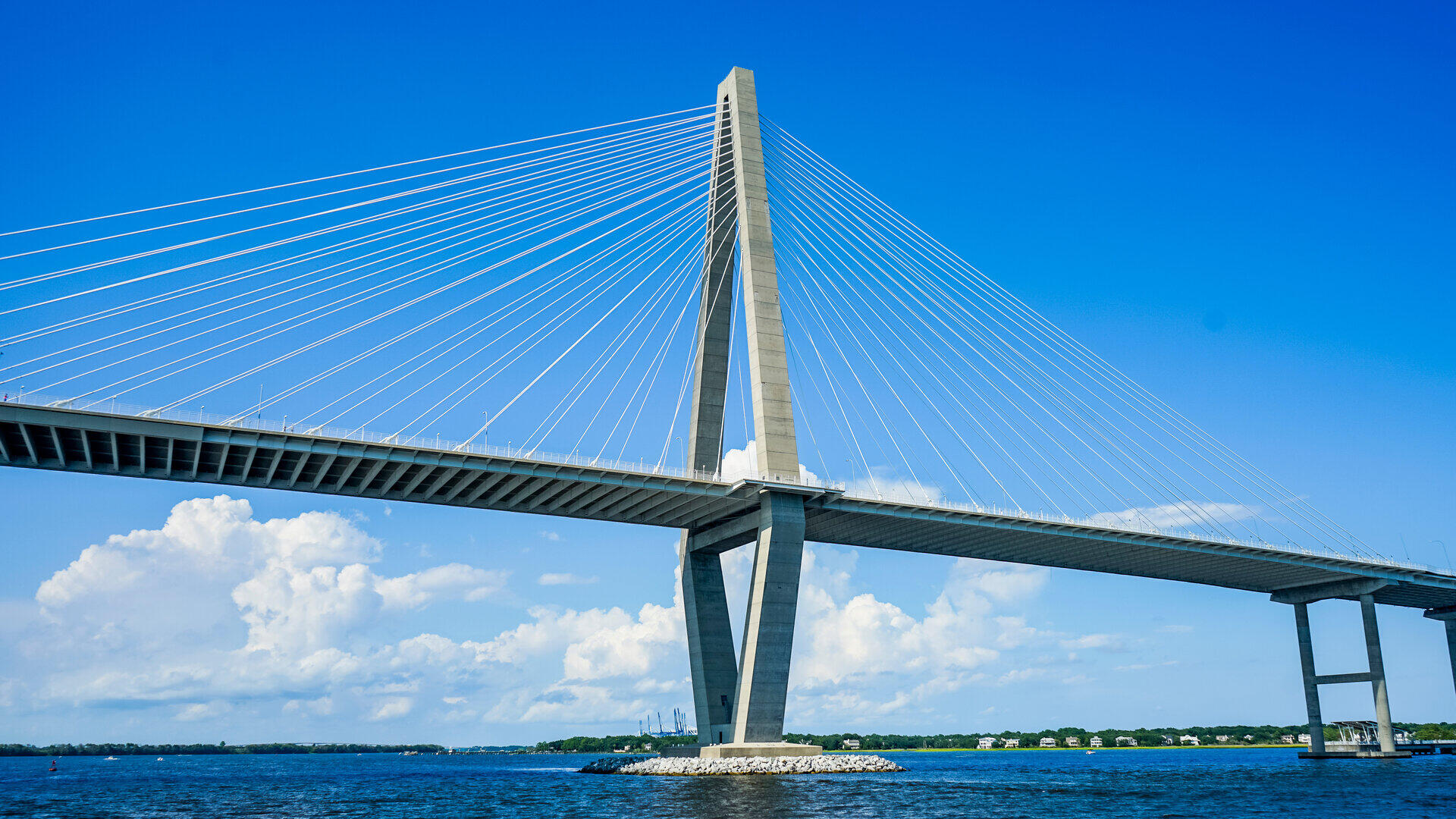 Wei&szlig;e Schr&auml;gseilbr&uuml;cke mit hohem Pylon vor blauem Himmel mit Wolken