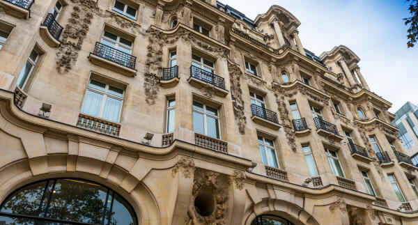 Aufwendig verzierte Fassade eines Altbaus mit Balkonen, von unten fotografiert