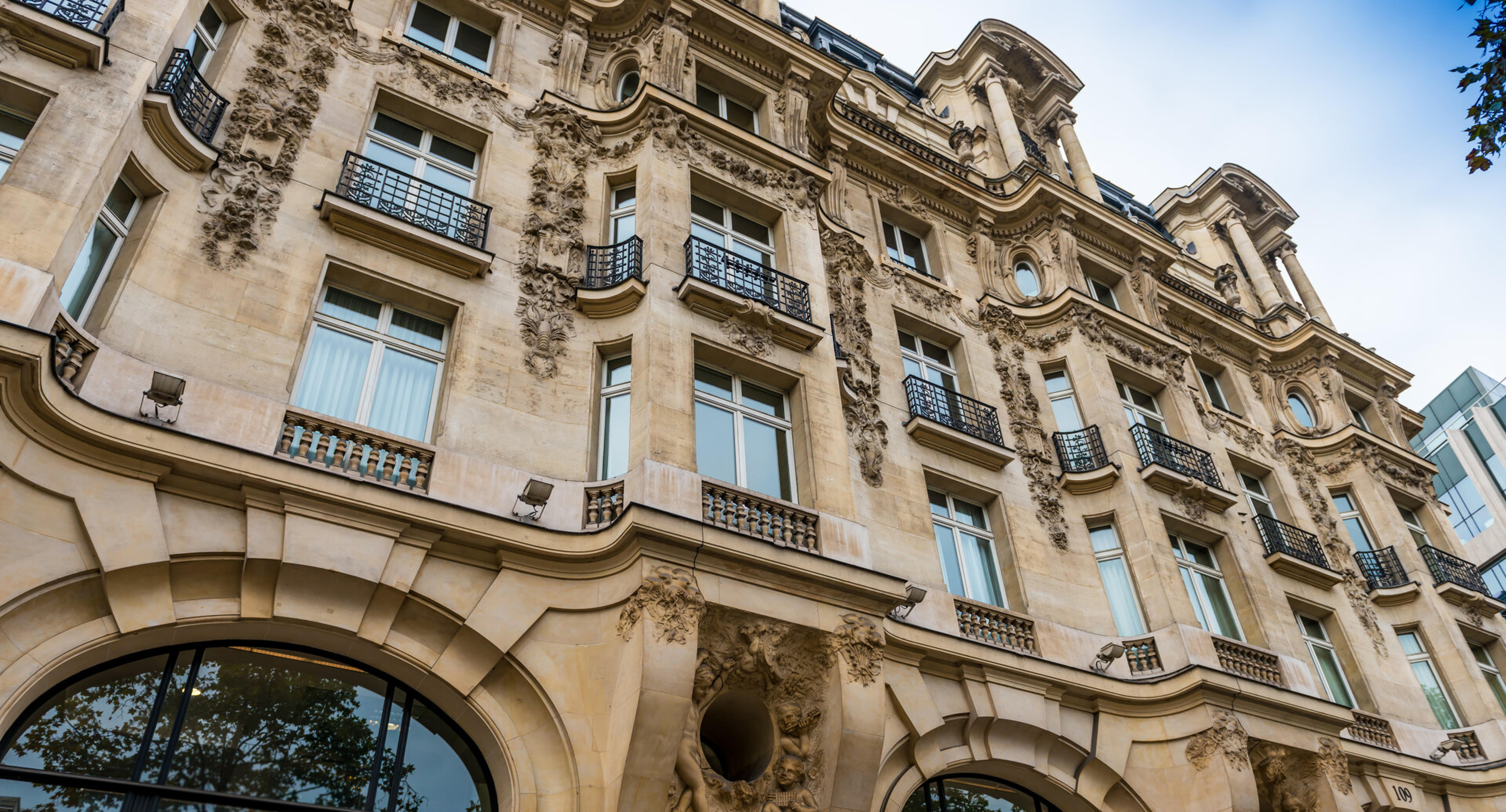 Aufwendig verzierte Fassade eines Altbaus mit Balkonen, von unten fotografiert
