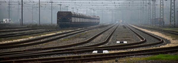 G&uuml;terwaggons auf einem nebligen Rangierbahnhof mit vielen Gleisen und Oberleitungen