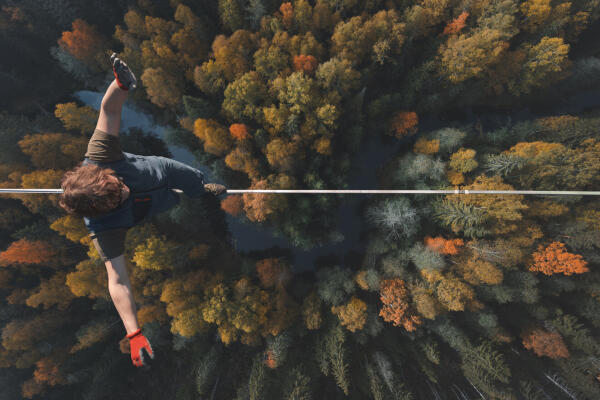 Luftaufnahme einer Person, die auf einer Slackline &uuml;ber herbstlichem Wald balanciert
