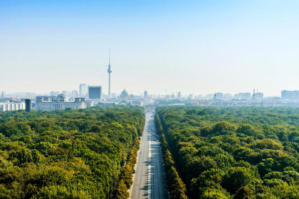 Berliner Skyline mit Fernsehturm hinter einer von B&auml;umen ges&auml;umten Allee