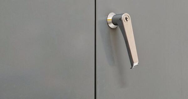 T&uuml;rklinke mit Schlie&szlig;zylinder an einer grauen Metallt&uuml;r in Nahaufnahme