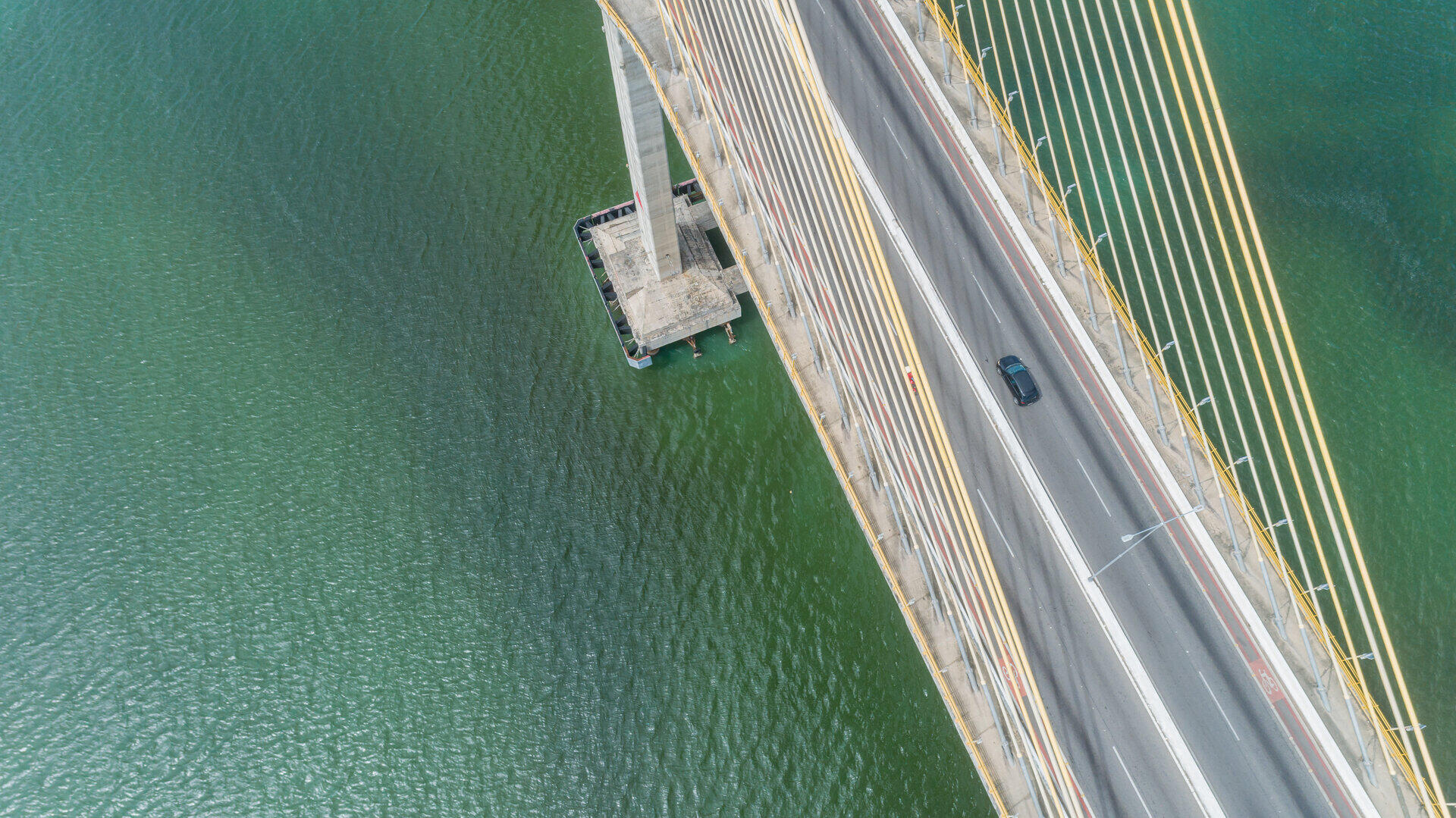 Luftaufnahme senkrecht von oben auf eine Schr&auml;gseilbr&uuml;cke mit einem Auto auf der Fahrbahn