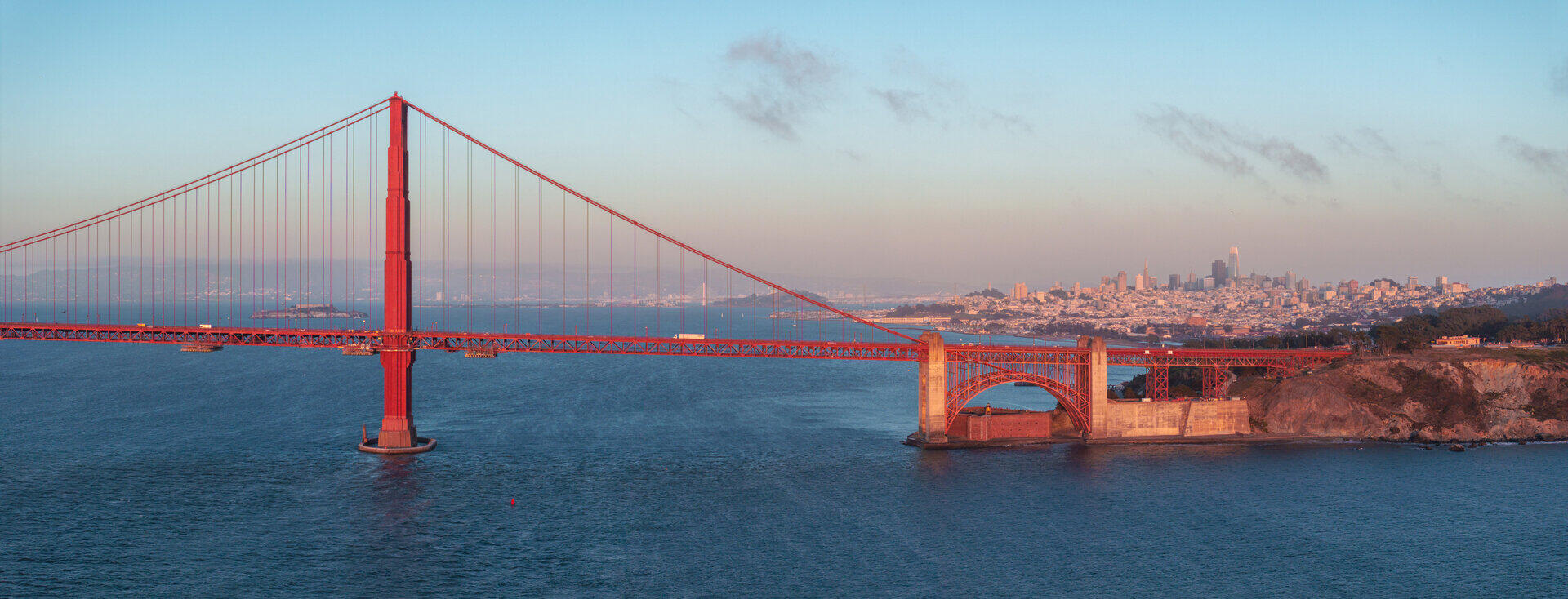 Golden Gate Bridge in Abendlicht, im Hintergrund die Skyline von San Francisco