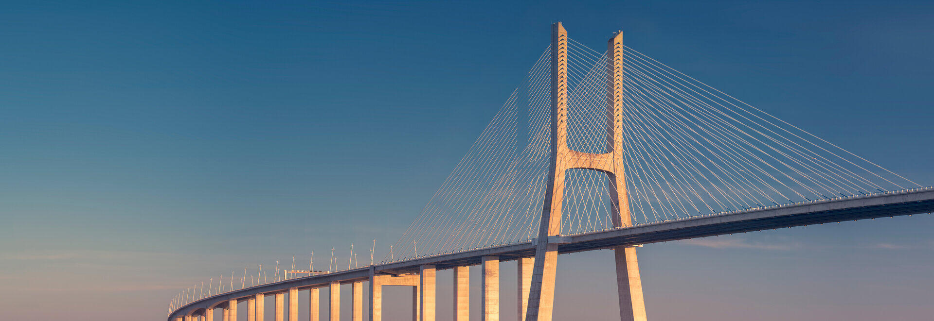 Schr&auml;gseilbr&uuml;cke im warmen Abendlicht &uuml;ber ruhigem Wasser