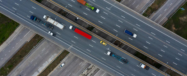 Luftaufnahme eines Autobahnkreuzes mit Lkw und Pkw auf sich kreuzenden Fahrbahnen