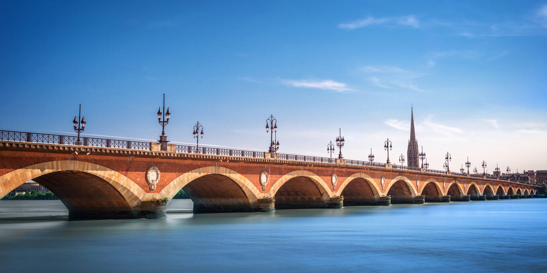 Historische Steinbogenbr&uuml;cke mit zahlreichen Laternen &uuml;ber einen Fluss