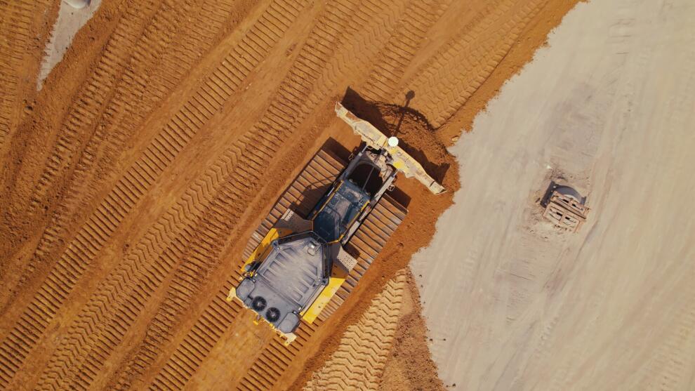 Luftaufnahme einer Planierraupe, die auf einer Baustelle Erdreich einebnet