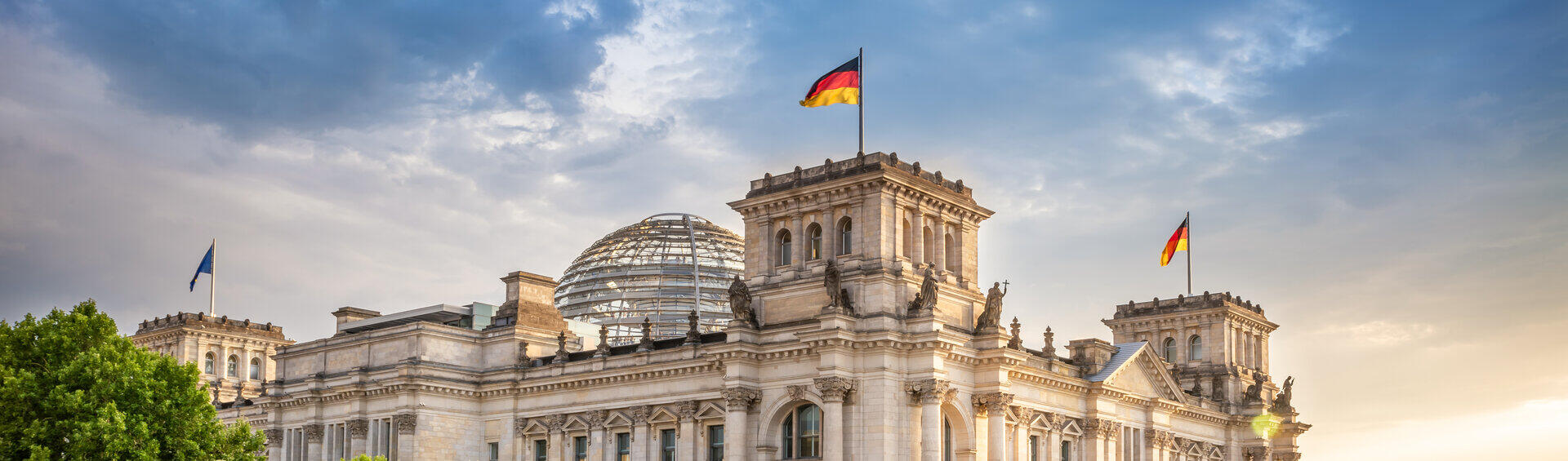 Reichstagsgeb&auml;ude in Berlin mit deutschen Flaggen am Spreeufer
