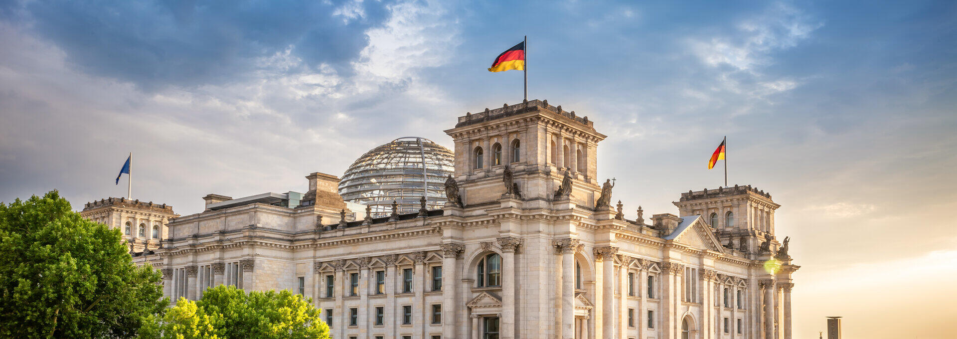 Reichstagsgeb&auml;ude in Berlin mit deutschen Flaggen am Spreeufer