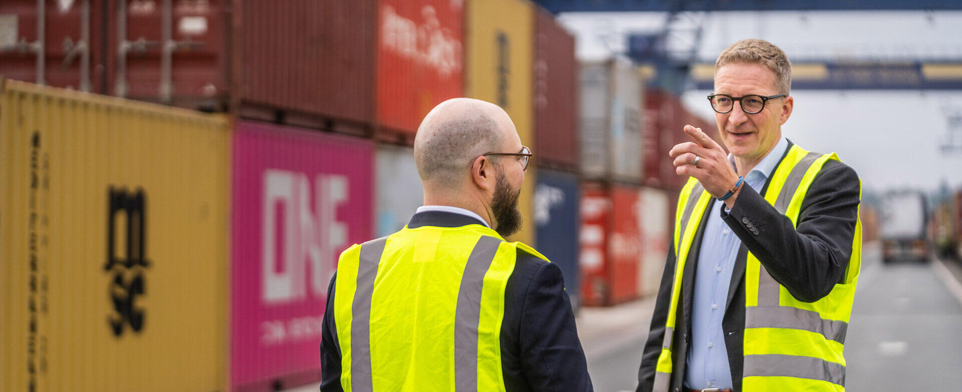 Rechtsanwalt Sebastian Harschneck in Warnweste im Gespr&auml;ch an einem Containerterminal