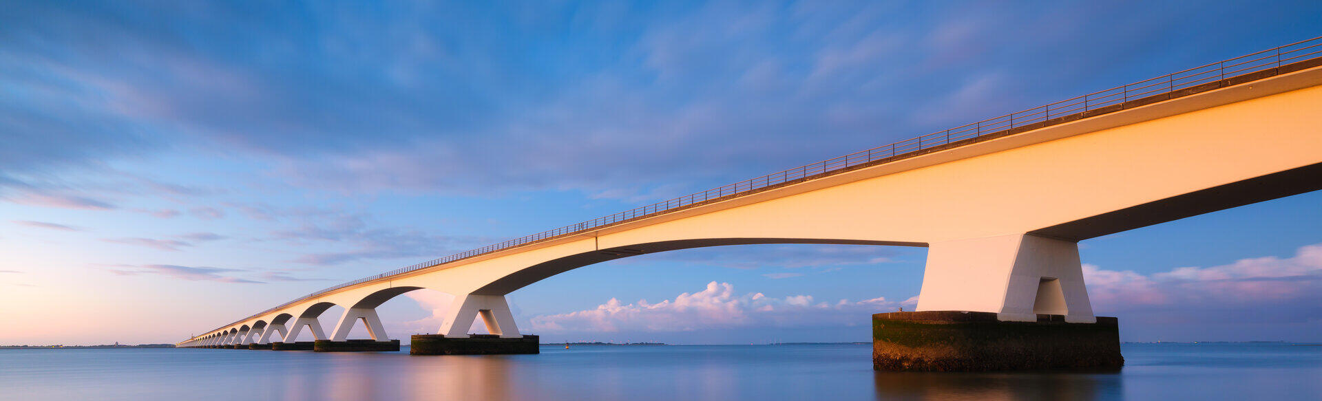 Lange Bogenbr&uuml;cke &uuml;ber ruhigem Meer in der Abendd&auml;mmerung