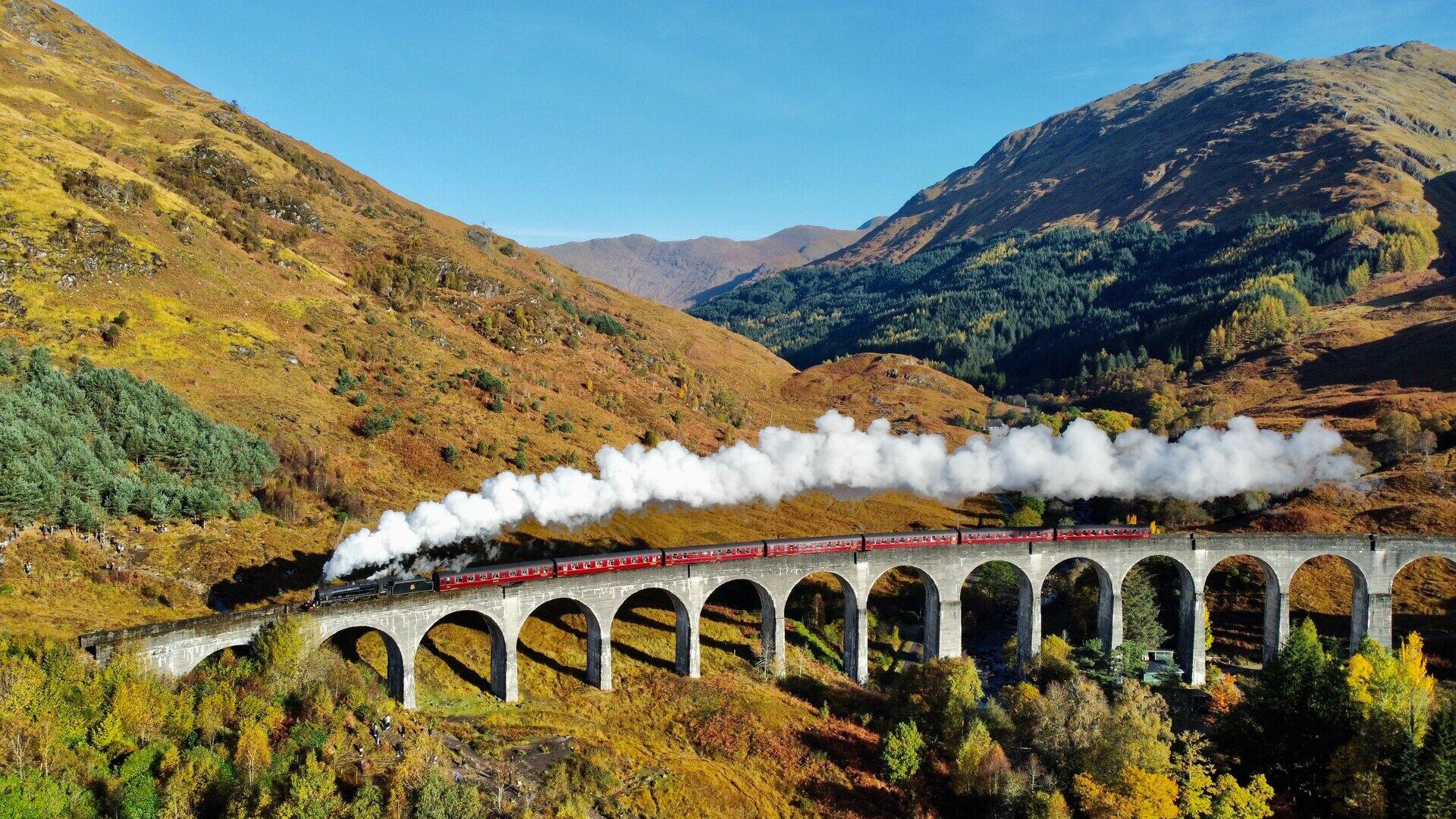 Dampfzug &uuml;berquert einen steinernen Viadukt in herbstlicher Berglandschaft