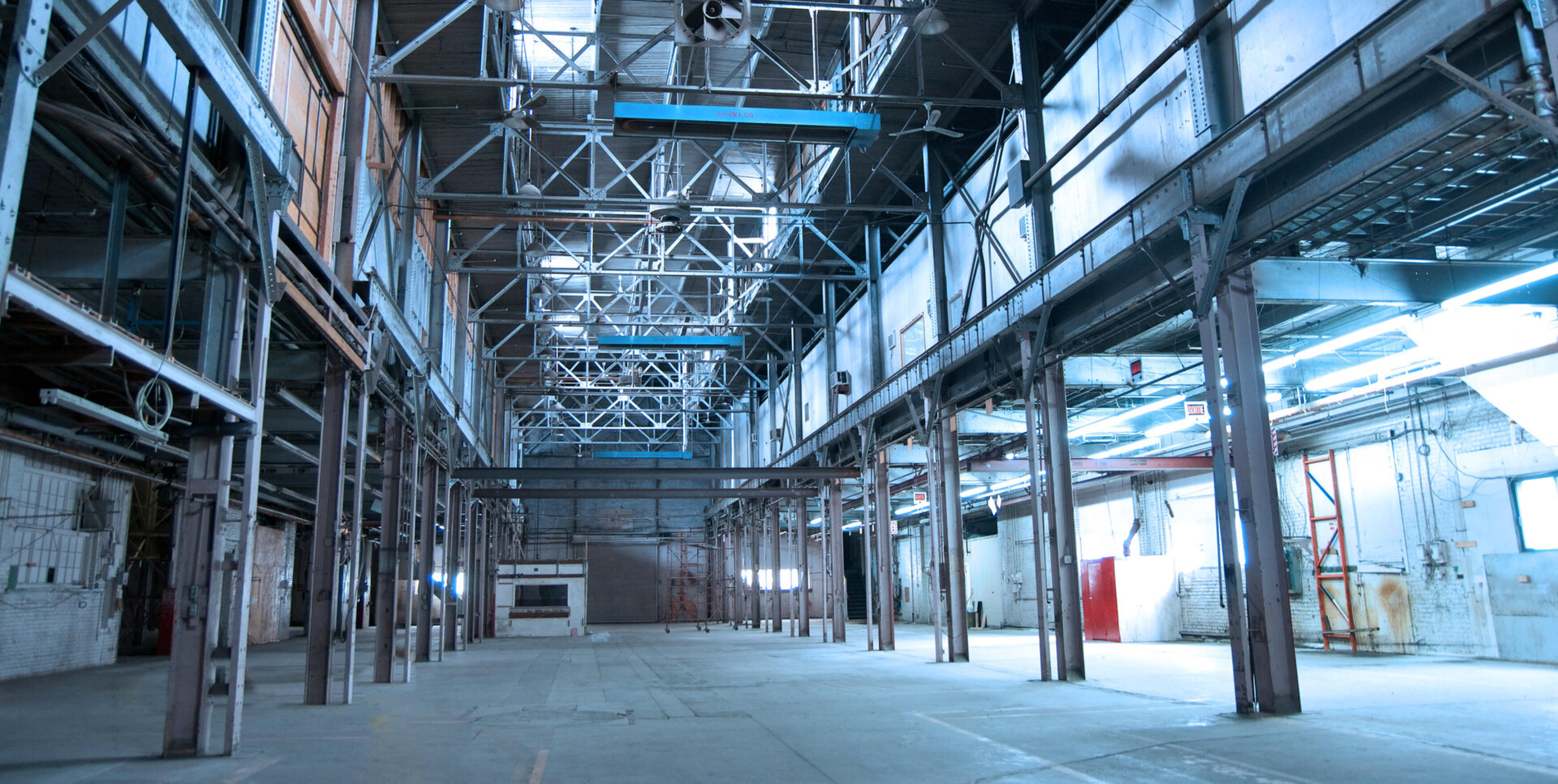 Leere, stillgelegte Fabrikhalle mit Stahltr&auml;gern in k&uuml;hlem blauem Licht