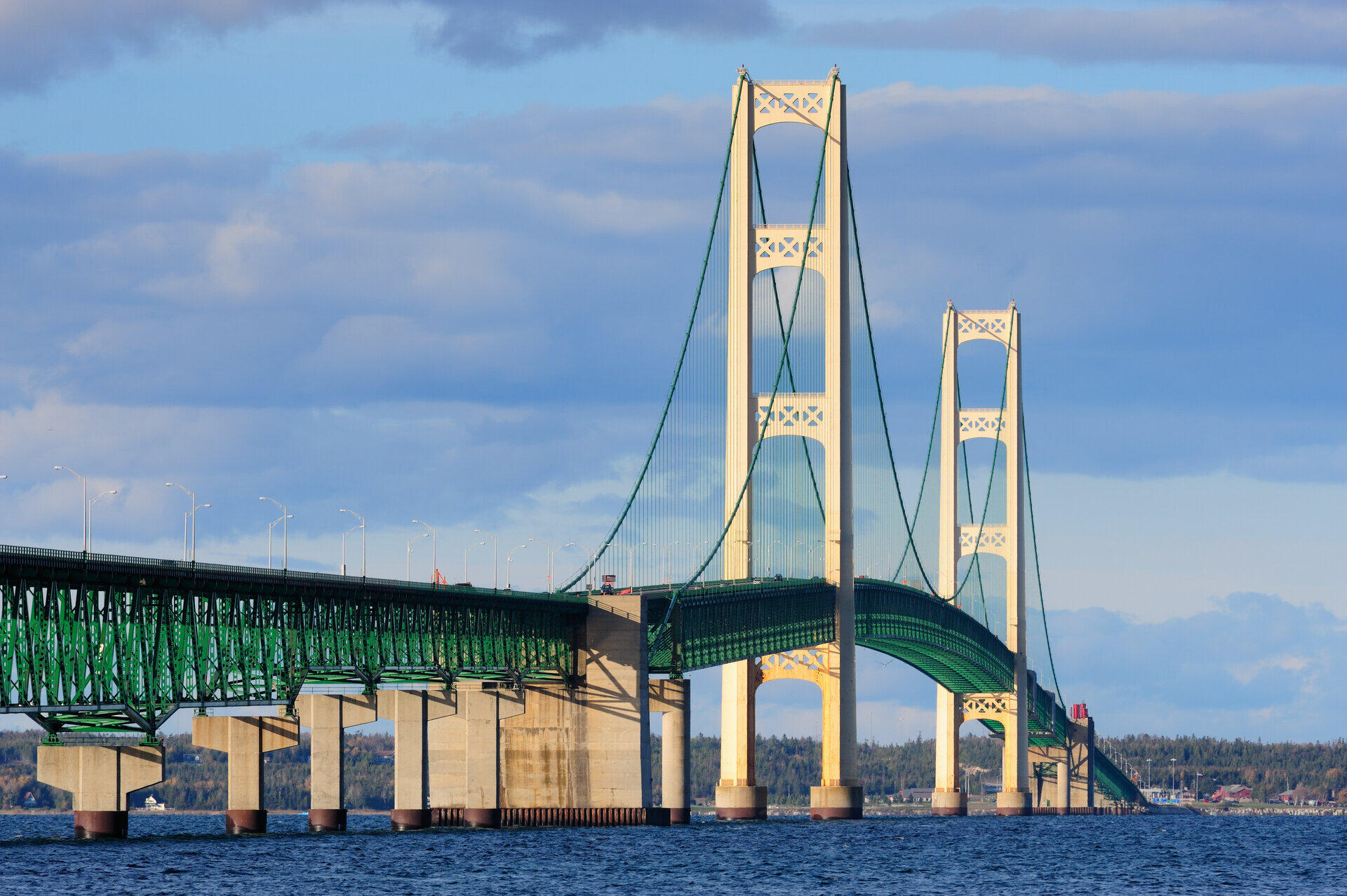 H&auml;ngebr&uuml;cke mit gr&uuml;n-wei&szlig;en Pylonen erhebt sich &uuml;ber blauem Wasser