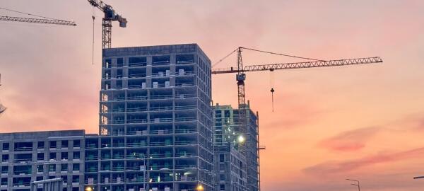 Baukr&auml;ne und ein Rohbau-Hochhaus vor orange-violettem Abendhimmel