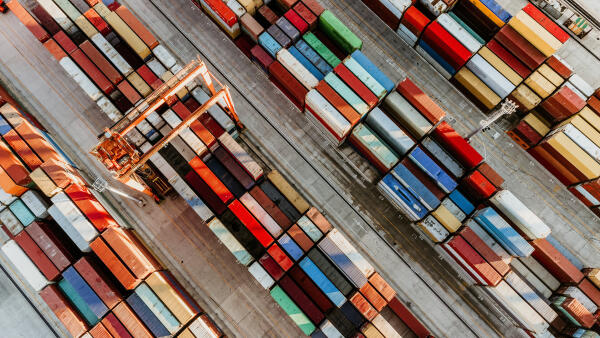 Containerterminal von oben mit Kran zwischen Reihen aus Frachtcontainern