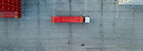 Luftaufnahme eines roten Schiffscontainers auf einem Lkw in einem Containerterminal