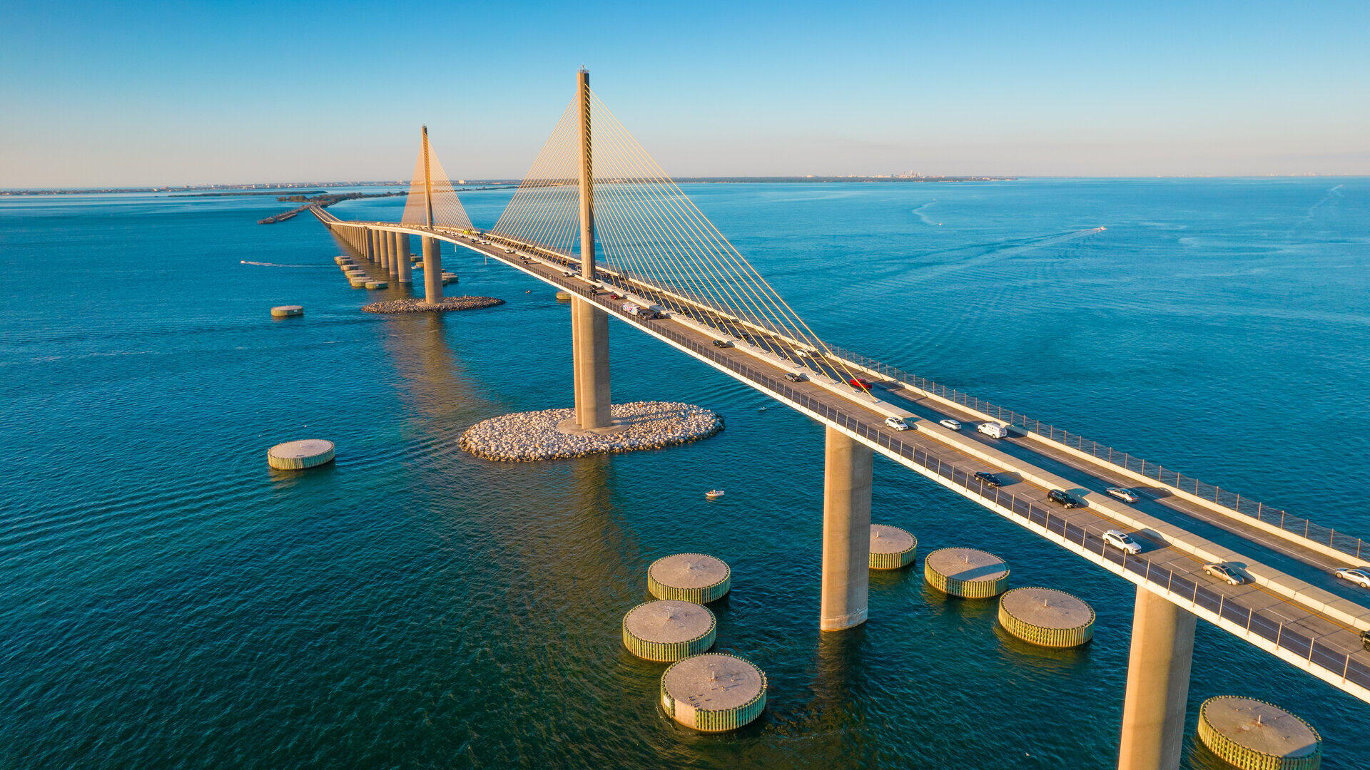 Schr&auml;gseilbr&uuml;cke mit gelben Pylonen &uuml;ber t&uuml;rkisfarbenem Wasser, Autos auf der Fahrbahn