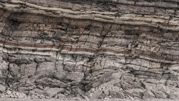 Freigelegte Gesteinsschichten einer Felswand im Querschnitt