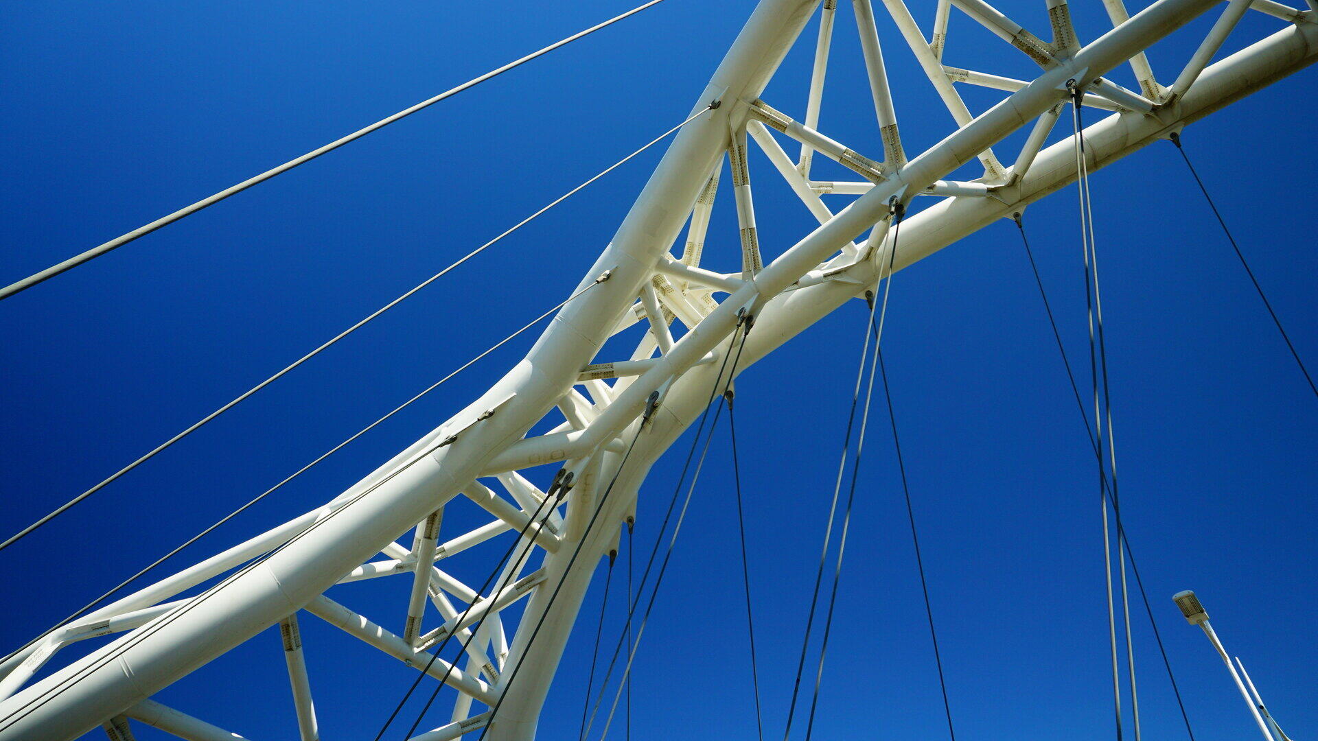 Wei&szlig;e Stahlfachwerkkonstruktion einer Bogenbr&uuml;cke vor blauem Himmel
