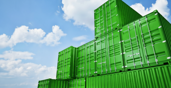 Gr&uuml;n gestapelte Frachtcontainer von unten fotografiert vor bew&ouml;lktem Himmel