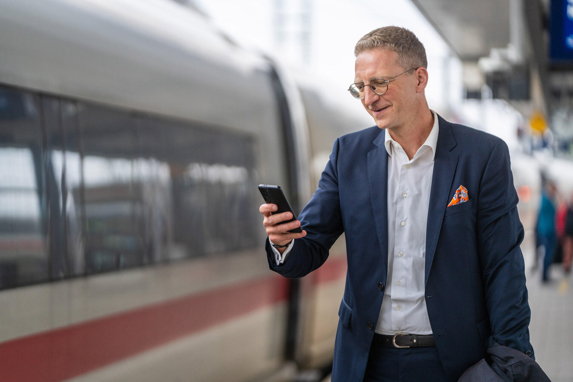 Lawyer Sebastian Harschneck checking his smartphone on a platform next to an ICE train