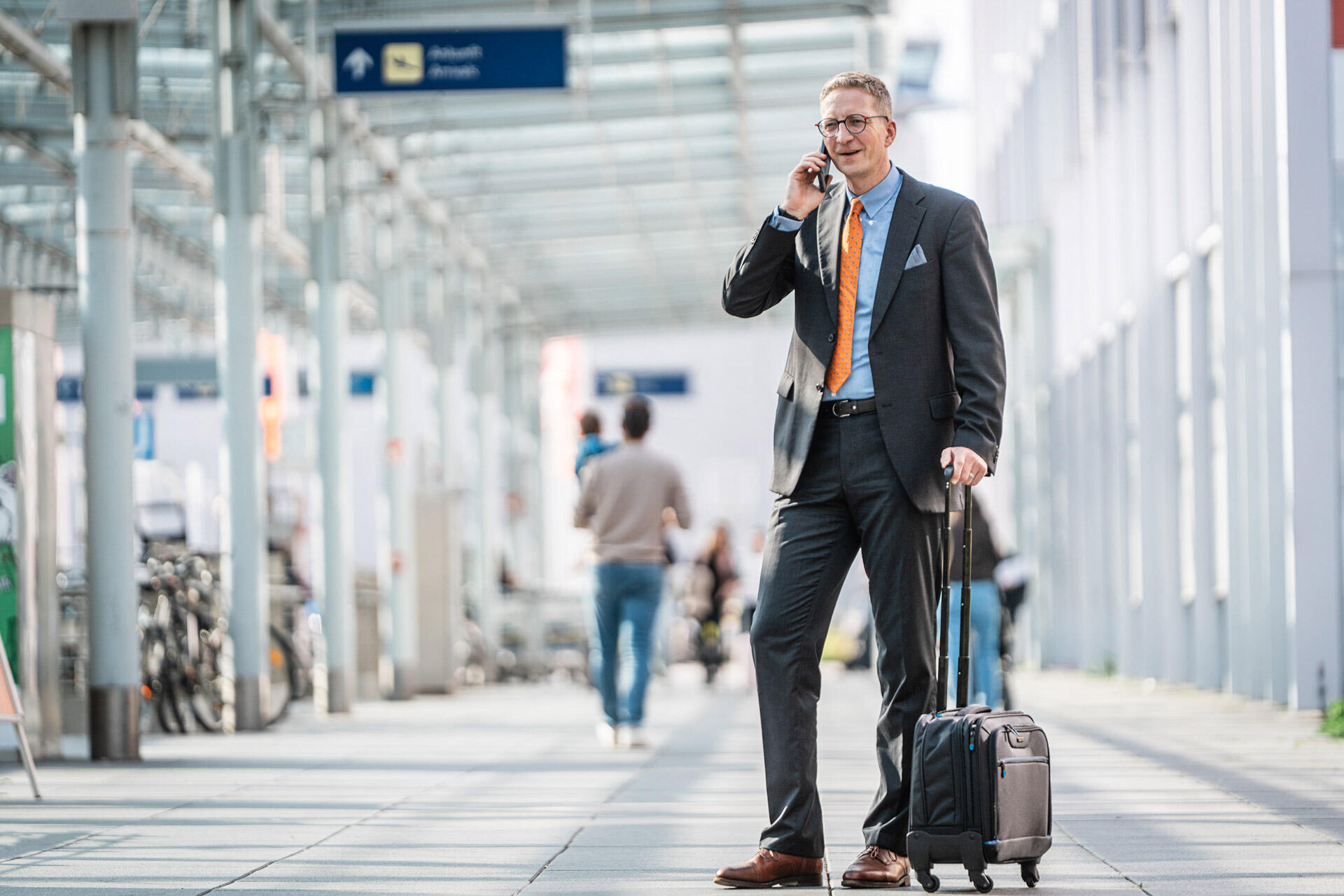 Portrait: Sebastian Harschneck on the phone with a rolling suitcase outside an airport