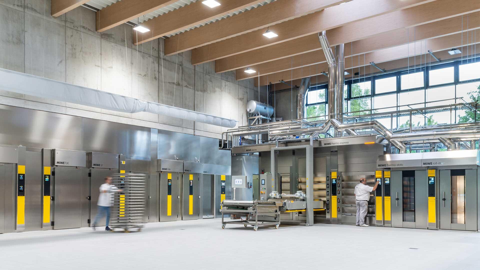 Backofenhalle von MIWE mit Edelstahl-&Ouml;fen und Mitarbeiter mit Stikkenwagen
